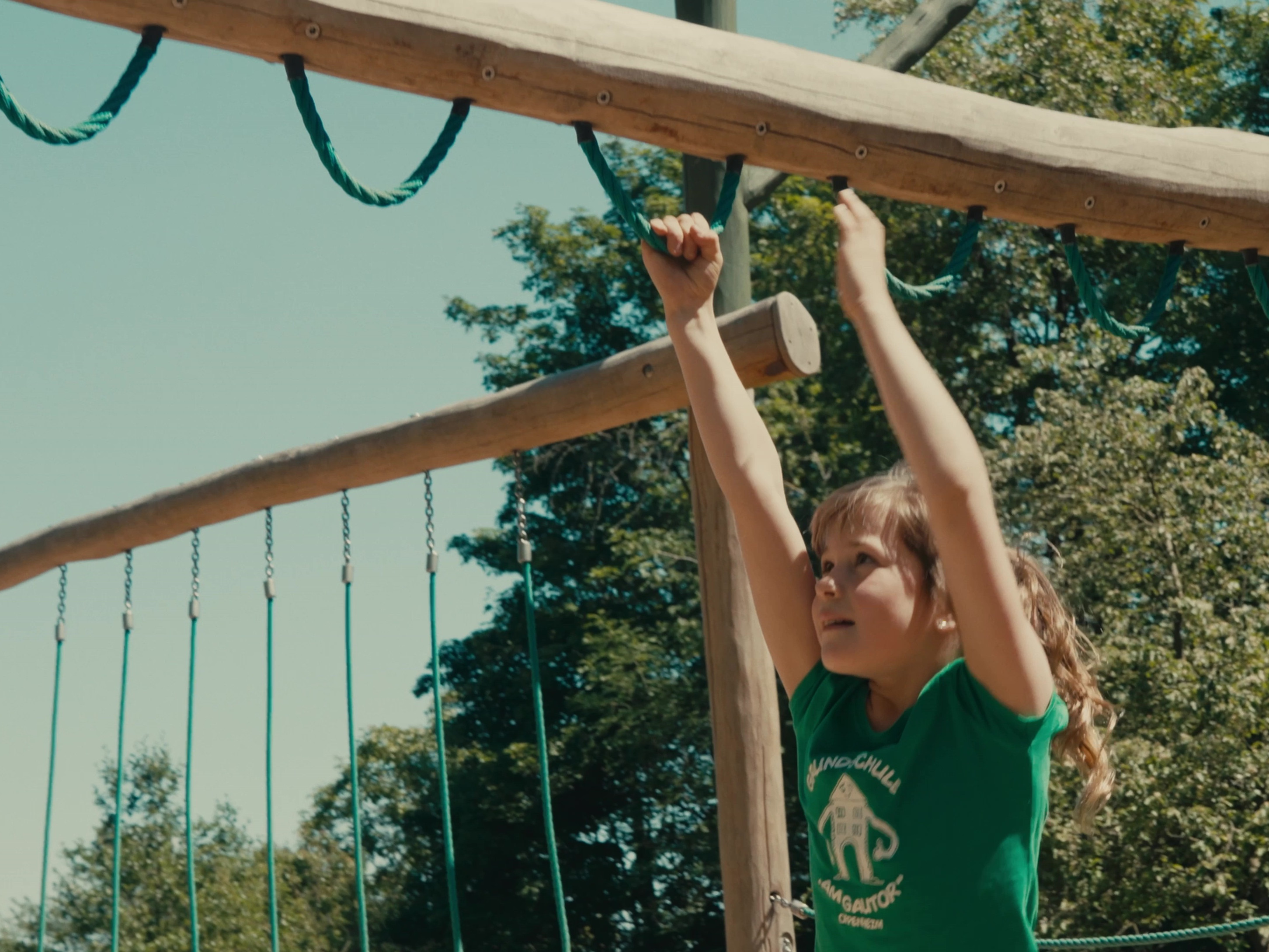 Spielplatz Ein Mädchen hangelt sich auf dem Spielplatz an Seilschlaufen entlang.