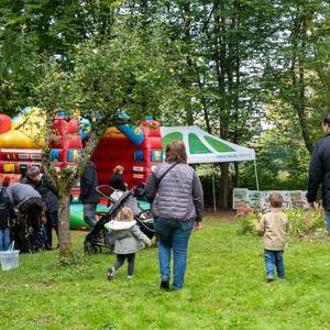 Das Bild zeigt Erwachsene und Kinder gehen in Richtung einer Hüpfburg