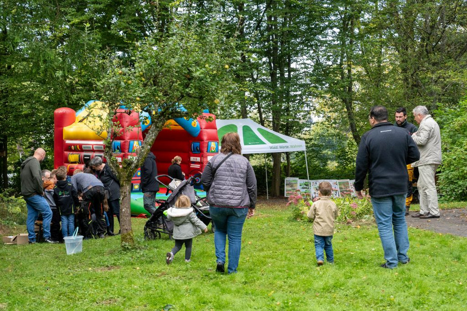 Das Bild zeigt Erwachsene und Kinder gehen in Richtung einer Hüpfburg
