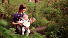Das Bild zeigt: eine Mutter mit ihrem Baby vor dem Bauch im Wald
