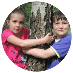 2 Kinder umarmen einen Baum, sind auf Tuchfühlung mit der Natur