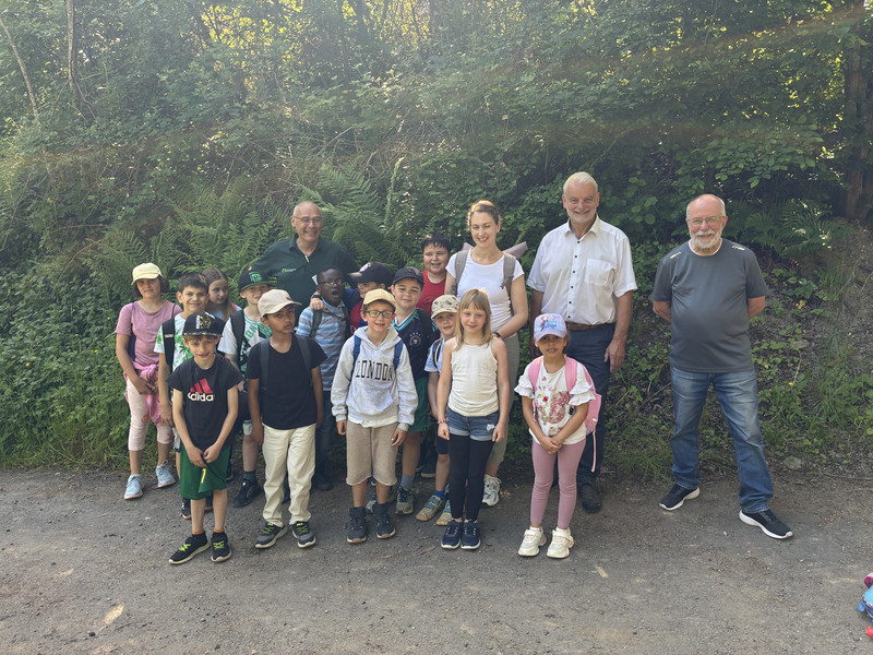 Bild: Die Klasse 3c der Grundschule St. Goarshausen mit ihrer Lehrerin Frau Schaust wartet gespannt auf ihren Start in den Waldparcours. Auch der Beigeordnete der VG Bad Ems-Nassau Birk Utermark und Ortsbürgermeister Klaus Poetzsch ließen es sich nicht nehmen, den Kindern in Begleitung von Forstamtsleiter Andreas Nick einen Besuch abzustatten.