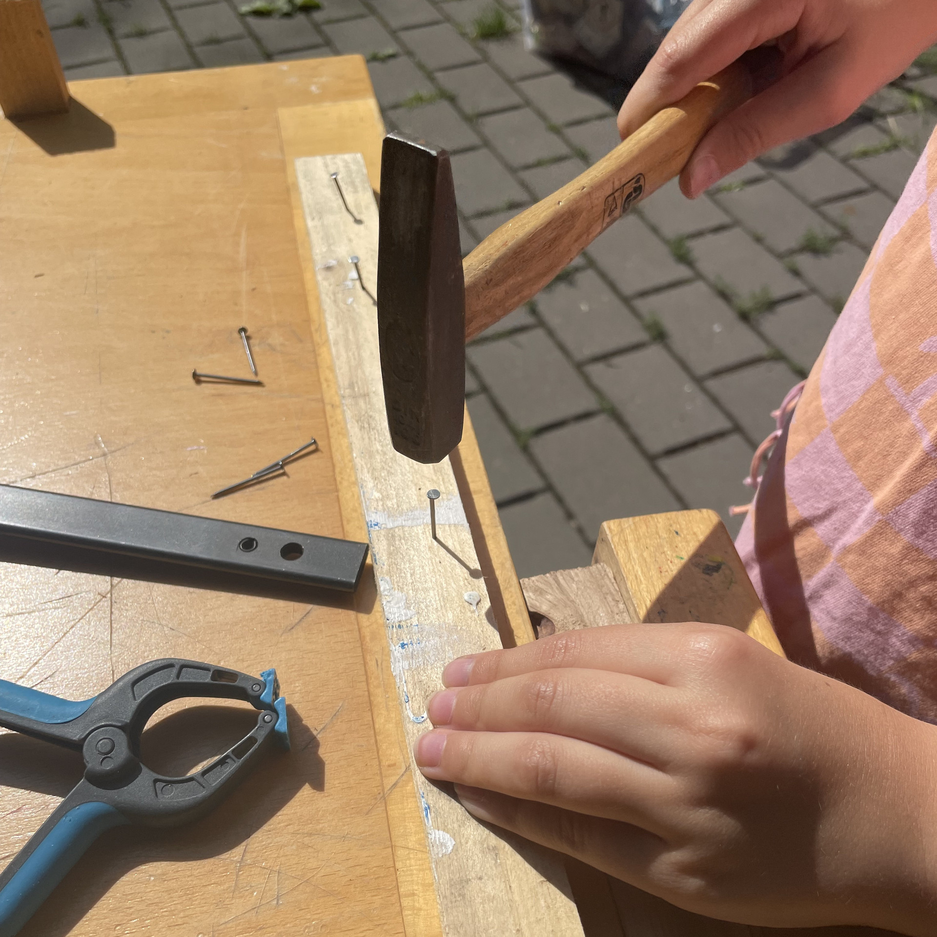 Holzwerken Hände schlagen mit einem kleinen Hammer einen Nagel in eine Holzleiste.