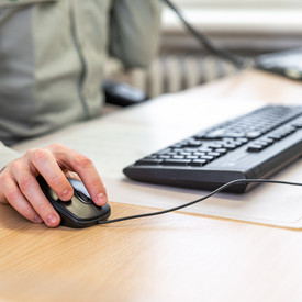 Das Bild zeigt die Hände einer Person beim Arbeiten am Computer.