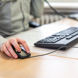 Das Bild zeigt die Hände einer Person beim Arbeiten am Computer.
