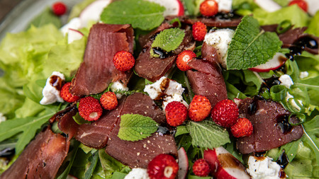 Im Bild zu sehen Wildcarpaccio auf Salat mit Erdbeeren und Mozzarellakäse