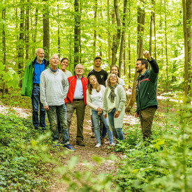 Gruppe von Erwachsenen mit einem Förster bei einer Führung im Wald